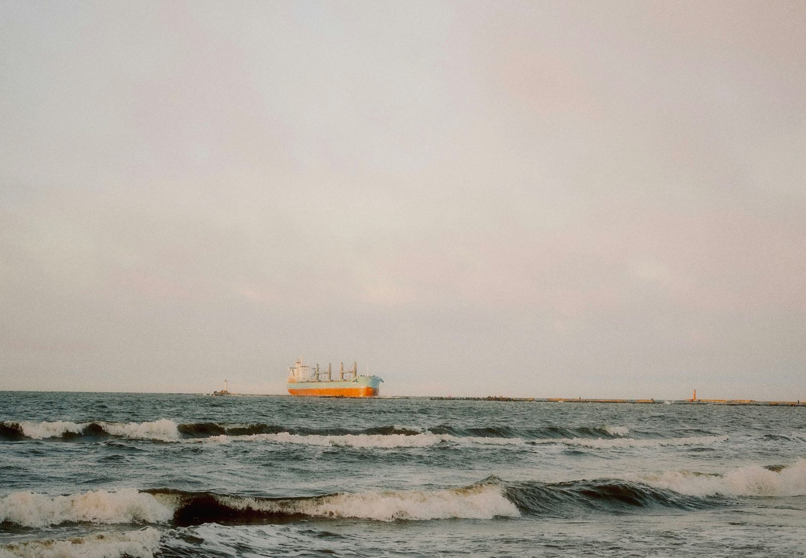 A real cargo ship on the sea at dusk, photographed by Ansis Kančs